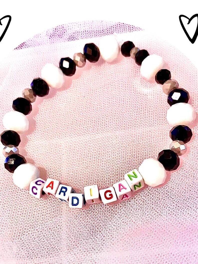 This black and white glass beaded bracelet, inspired by Taylor Swift's "Cardigan," captures the song's cozy, nostalgic vibe. Handcrafted for Swifties, it embodies the soft and timeless elegance of the *Folklore* era the perfect collectible accessory.