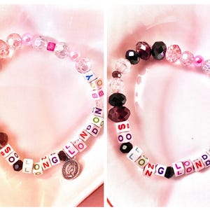 May include: Two bracelets with colourful letter beads spelling out "SO LONG LONDON" and "SO LONG LONDON" with a charm on one bracelet. The bracelets are made with clear, pink, and brown beads.