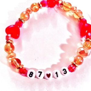 Red and gold handmade “87❤️13” beaded bracelet inspired by Taylor Swift and Travis Kelce with heart accents and stretchy elastic cord. Celebrity couple inspired jewelry perfect for game day outfits, matching friendship bracelets, sporty glam accessories, handmade Swiftie collectibles, trending fan jewelry, romantic concert accessories, and gifts for music lovers and football fans.