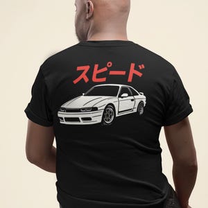 May include: A black t-shirt with a white silhouette of a car and the Japanese word "Speed" in red on the back.
