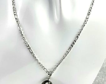 May include: A silver-toned necklace featuring a key pendant. The key has a dark, aged appearance, contrasting with the bright chain. The chain is a classic link style, and the necklace is displayed on a white mannequin.