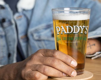 May include: A tall glass of beer with a white head, featuring the text "Paddy's Irish Pub South Philadelphia" on the side.