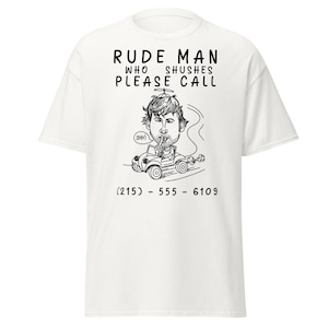 May include: White t-shirt with a black and white illustration of a man driving a car with the text "Rude Man Who Shushes Please Call (215) - 555 - 6109".
