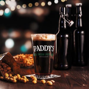 May include: A glass of dark beer with a thick head of foam. The glass has a logo that reads "Paddy's Irish Pub, South Philadelphia".