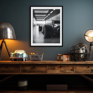 Dramatic black and white art print of a Formula 1 car parked in a well-lit garage, highlighting the precision and allure of high-speed racing. Ideal for car lovers, adding bold style to man caves and home offices. f1 wall art, f1 poster