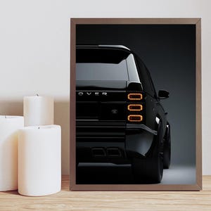 Puede incluir: Un Range Rover negro con las luces traseras iluminadas. El coche está aparcado en una superficie gris. La palabra "Rover" es visible en la parte trasera del coche.