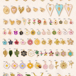 K&ouml;nnte beinhalten: Eine Sammlung verschiedener Metallanh&auml;nger mit den Nummern 235 bis 319, die verschiedene Formen wie Herzen, Blumen, Bl&auml;tter, Kakteen und Palmen aufweisen, wobei einige Designs Emaillierungen und kleine klare Kristalle enthalten.