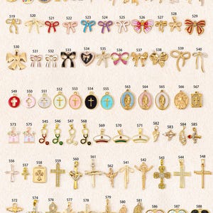 K&ouml;nnte beinhalten: Eine Sammlung von Metallanh&auml;ngern mit verschiedenen Motiven wie Schleifen, Kreuzen, religi&ouml;sen Figuren, Herzen und Symbolen, die jeweils mit einer eindeutigen Identifikationsnummer von 505 bis 588 versehen und in einem Raster angeordnet sind.