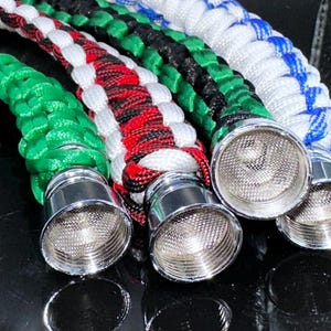 May include: Four braided paracord pipes with different color combinations, each with a metal bowl and a screen. The colors are green, red and black, white and black, and white and blue.