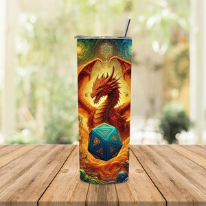 K&ouml;nnte beinhalten: Ein Edelstahlbecher mit einem farbenfrohen Design, das einen roten Drachen und einen blauen und gr&uuml;nen W&uuml;rfel zeigt. Der Drache ist von einem wirbelnden Muster aus Gold, Blau und Gr&uuml;n umgeben.
