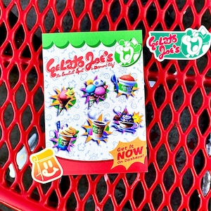 Op de afbeelding: Een rechthoekige flyer voor Gelato Joe's met kleurrijke illustraties van ijs, slushies en koffiedrankjes. De tekst luidt Gelato Joe's The Sweetest Spot in Diamond City! en Get It NOW On Dashapp! Twee extra stickers zijn inbegrepen.