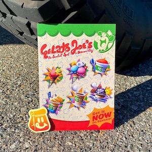 Op de afbeelding: Een rechthoekige flyer voor Gelato Joe's met de tekst Gelato Joe's The Sweetest Spot in Banana City! en Get It Now On Dashapp! Het ontwerp toont kleurrijke illustraties van ijs, ijscoupes en drankjes met een kleine sticker van een tas.