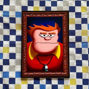 May include: A framed cartoon portrait of a stern-faced man with red hair, a red shirt with a yellow collar, and a whistle pendant. The frame is brown with ornate detailing. The background is a blue gradient.