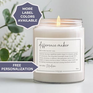 May include: A white candle with a glass jar and a label that reads "difference maker" with a definition of the word. The candle is 9 oz and has a free personalization option.