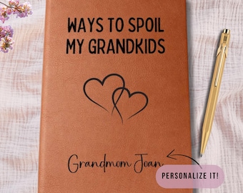 Op de afbeelding: Een bruin leren notitieboek met de zwarte tekst "WAYS TO SPOIL MY GRANDKIDS". Twee in elkaar grijpende harten staan eronder. De naam "Grandmom Joan" staat eronder. Een gouden pen ligt rechts.