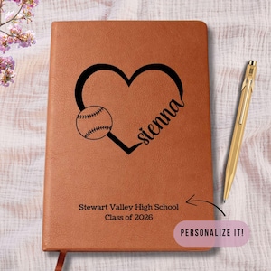 May include: A brown leather journal with a baseball design and the name "sienna" in script. The journal also features the text "Stewart Valley High School Class of 2026". A gold pen rests beside the journal. The image includes the text "PERSONALIZE IT!"