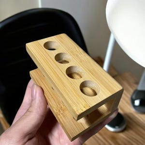 Puede incluir: Un organizador de bambú natural con cinco ranuras redondas para guardar objetos como bolígrafos, lápices o pinceles de maquillaje.