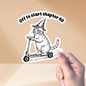 May include: A black and white sticker featuring a cat wearing a wizard hat and riding a scooter. The sticker has the text "Off to start chapter 60" in a circular design.