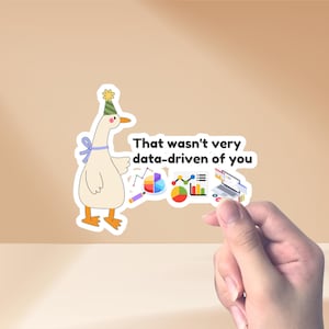 以下が含まれることがあります： パーティーハットとリボンをつけた漫画のガチョウのステッカー。ステッカーには「That wasn't very data-driven of you」というテキストとデータ分析グラフィックが描かれています。ステッカーは手で持たれています。
