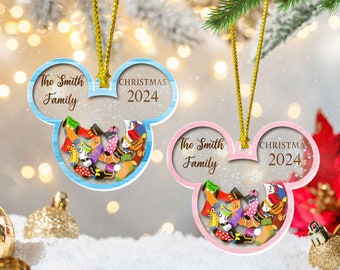 May include: Two Christmas ornaments in the shape of Mickey Mouse heads. One is light blue, the other pink. Both have the text "The Smith Family" and "CHRISTMAS 2024". Inside each is a collection of colorful socks.
