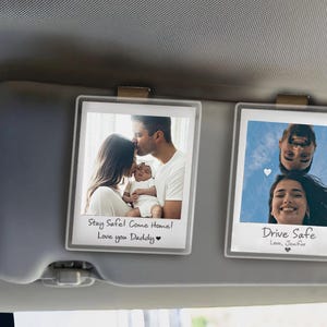 May include: Two white photo frames with black borders, each containing a photo. The top frame shows a family with a baby and the text "Stay Safe! Come Home! Love you Daddy". The bottom frame shows a couple and the text "Drive Safe Love, Jennifer".