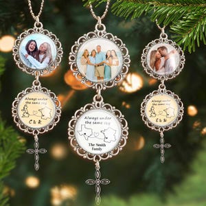 Puede incluir: Collares colgantes plateados con marcos de fotos circulares y dijes de cruz. Los colgantes presentan fotos familiares y el texto "Always under the same sky" con ilustraciones de mapas y nombres. También se muestra The Smith Family.
