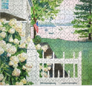 May include: A watercolor painting of a white picket fence with a gate leading to a view of a lake with boats. The fence is surrounded by a lush green lawn and a white house with a red, white, and blue American flag hanging from the porch. There are white flowers blooming in the foreground.