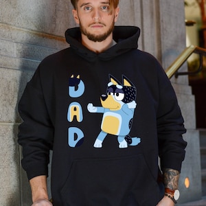 a man wearing a black hoodie with a cartoon character on it