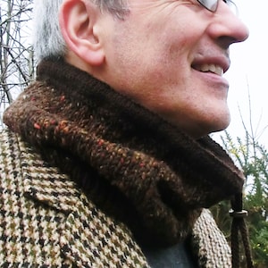 Puede incluir: Un hombre con una chaqueta de estampado marrón y blanco con un cuello de lana marrón. El cuello tiene un cordón largo con un cierre metálico.