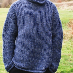 May include: A blue knitted sweater with a high neck and long sleeves.