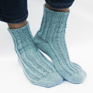 May include: A pair of light blue knitted socks with a cable knit pattern.