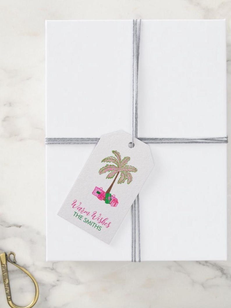 Puede incluir: Una etiqueta de regalo rosa y verde con una palmera y regalos. El texto en la etiqueta dice "Warm Wishes The Smiths".