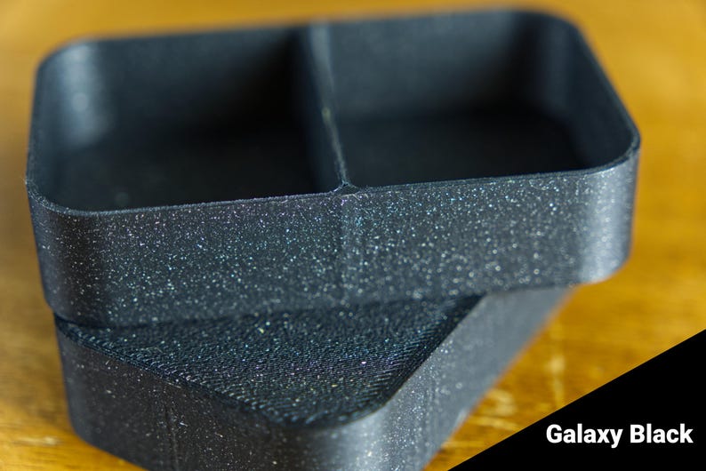 May include: Two black plastic containers with a speckled finish. The containers are stacked on top of each other. The top container has two compartments. The bottom container is a single compartment. Galaxy Black.