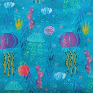 May include: A teal blue fabric with a repeating pattern of purple, blue, and yellow jellyfish, coral, and seaweed. The background is a light blue with white dots.