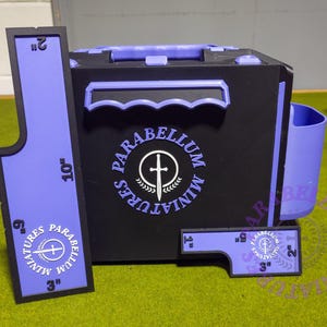 May include: A black and purple miniature storage box with matching measuring tools. The box has a handle and a side cup holder. The measuring tools are labeled with inches. The text "S. PARABELLUM MINIATURES" is displayed on the box and tools.