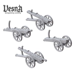 May include: Four gray miniature cannons with wooden wheels and carriages are displayed against a white background. The cannons are designed for wargaming scenery, as indicated by the text "Vesna wargaming scenery" in the upper left corner.