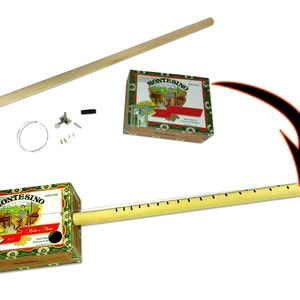 May include: A DIY cigar box guitar kit. The kit includes a cigar box, a wooden neck with frets, strings, tuning pegs, and other hardware. The cigar box has a colorful label with text and illustrations.