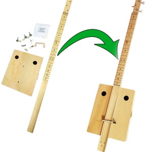 Puede incluir: Un kit de guitarra de caja de puros de madera con acabado de madera natural. El kit incluye una caja de madera, un mástil de madera y herrajes. El mástil se muestra por separado de la caja, con una flecha que indica que el mástil debe fijarse a la caja.
