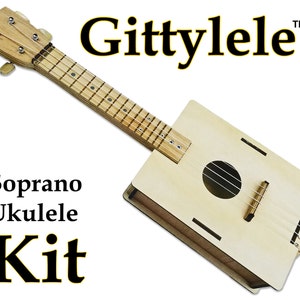 Könnte beinhalten: Ein Ukulelen-Set aus Holz mit der Aufschrift "Gittylele" und "Soprano Ukulele Kit" in schwarzer Schrift. Die Ukulele ist aus hellem Holz gefertigt und hat eine natürliche Oberfläche.