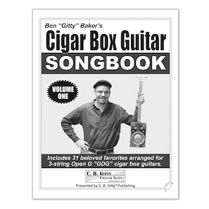 Puede incluir: Portada en blanco y negro de un cancionero para guitarras de caja de puros. La portada presenta a un hombre sosteniendo una guitarra de caja de puros y el título "Ben "Gitty" Baker's Cigar Box Guitar Songbook, Volume One".