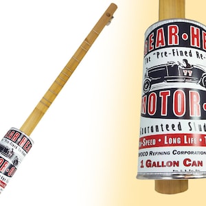 May include: A wooden cigar box guitar with a vintage oil can design. The can features a red and black logo that reads "Gear-Head Motor Oil" and a vintage car illustration. The text on the can reads "The "Pre-Fined Re-Fined" Guaranteed Sludge-Free High-Speed Long Life Triple-X MOCO Refining Corporation Oil 1 Gallon Can 75c".