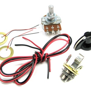 Op de afbeelding: Een DIY elektrische gitaar pickup kit met twee goudkleurige piezo pickups, een zwarte knop, een rode en zwarte draad, een potentiometer met een 3-positieschakelaar en een 1/4-inch uitgangsaansluiting.