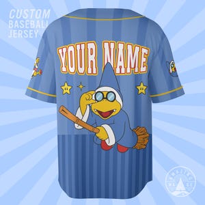 May include: A light blue baseball jersey with vertical stripes, featuring the text "CUSTOM BASEBALL JERSEY" and "YOUR NAME" in orange and white. A yellow turtle character in a blue wizard hat and robe rides a broomstick with yellow stars.