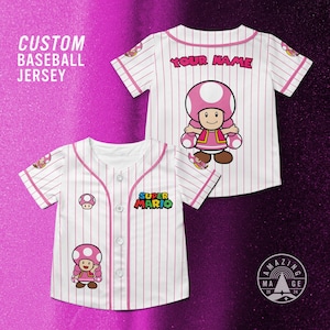 May include: White baseball jersey with pink pinstripes, featuring a Super Mario character design. The jersey has a mushroom patch, the words "SUPER MARIO", and the text "YOUR NAME" on the back. The words "CUSTOM BASEBALL JERSEY" are also visible.