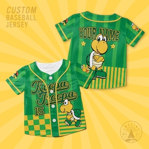 May include: Green custom baseball jersey with Koopa Troopa graphics. The front features the text "Koopa Troopa" and the number 15. The back has the text "YOUR NAME" above a Koopa Troopa character. The jersey has a button-up front and yellow accents.