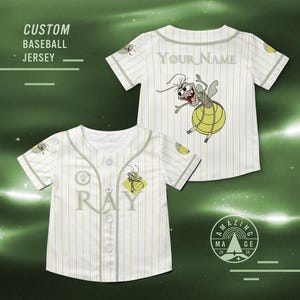 May include: White baseball jersey with vertical yellow stripes, featuring a cartoon firefly graphic and the text "RAY". The jersey has a button-up front and a grey collar and sleeve trim. The text "CUSTOM BASEBALL JERSEY" is also visible.