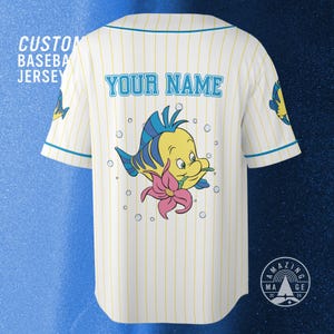 May include: Custom baseball jersey with a yellow and blue cartoon fish design on the back, surrounded by bubbles. The jersey is white with yellow vertical stripes and blue trim. The text "YOUR NAME" is above the fish.