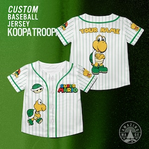 May include: White baseball jersey with green pinstripes and a Koopa Troopa design. The jersey features the text "CUSTOM BASEBALL JERSEY KOOPA TROOP" and "SUPER MARIO". The back of the jersey has the text "YOUR NAME" and a Koopa Troopa character.