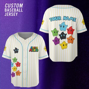 May include: A white baseball jersey with thin yellow pinstripes and light blue trim. The front features the text SUPER MARIO and colorful star characters. The back displays the text YOUR NAME above a cluster of various colored star characters.