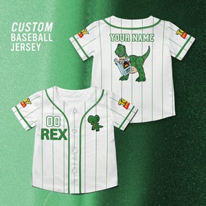 Puede incluir: Camiseta de b&eacute;isbol blanca con finas rayas verdes y detalles. La camiseta muestra "REX" y "00" en la parte delantera. La parte trasera presenta un dinosaurio de dibujos animados leyendo un libro, con "YOUR NAME" encima. Mangas cortas.